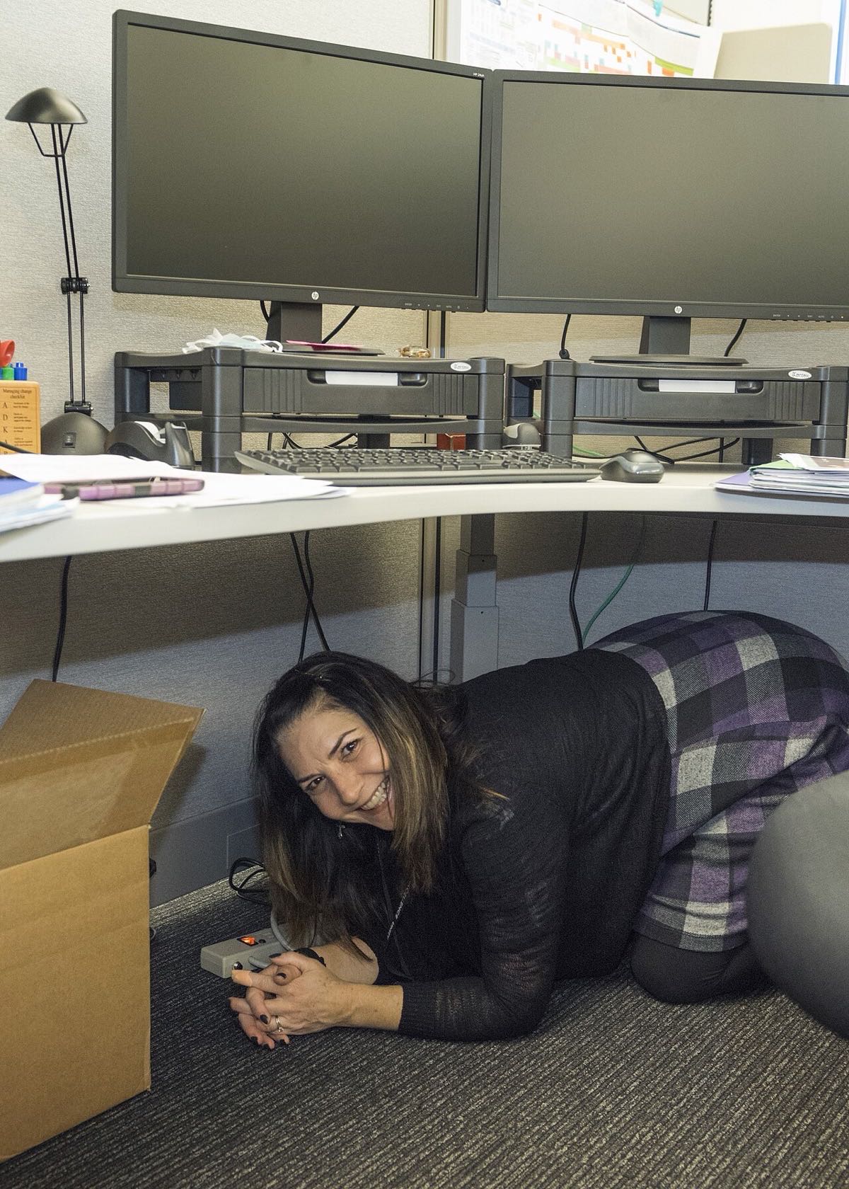 Person practicing Drop, Cover, Hold On beneath an office desk during an earthquake drill