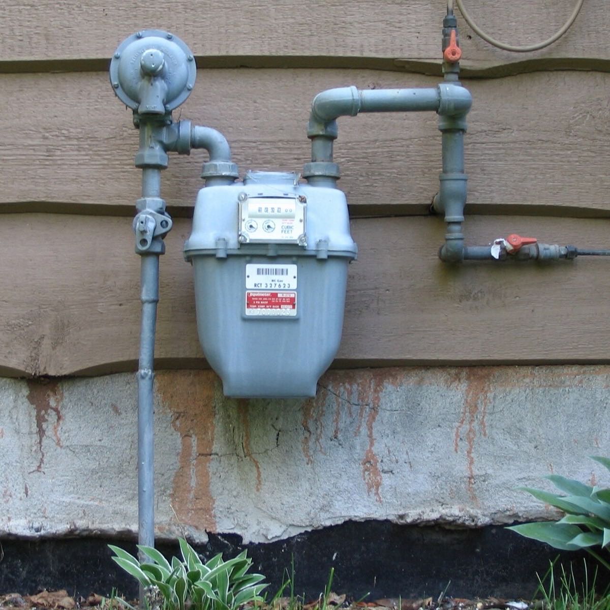 Household gas meter with piping and two quarter-turn shutoff valves with red handles