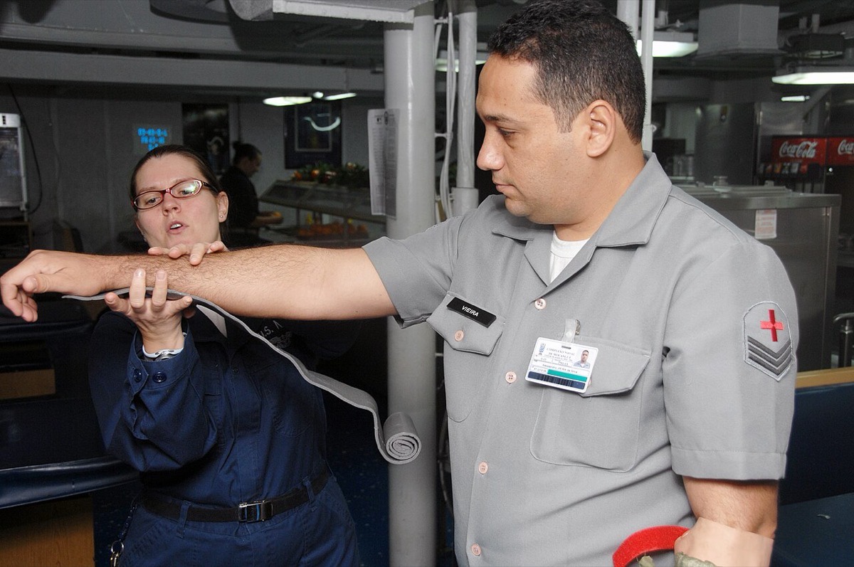 Instructor demonstrating how to apply a rolled splint along a volunteer's extended forearm